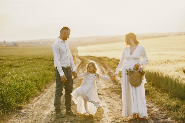 Family with little daughter spending time together in sunny field