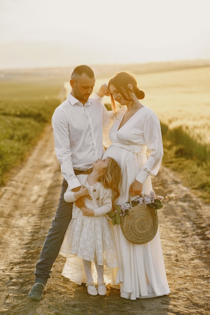 Family with little daughter spending time together in sunny field