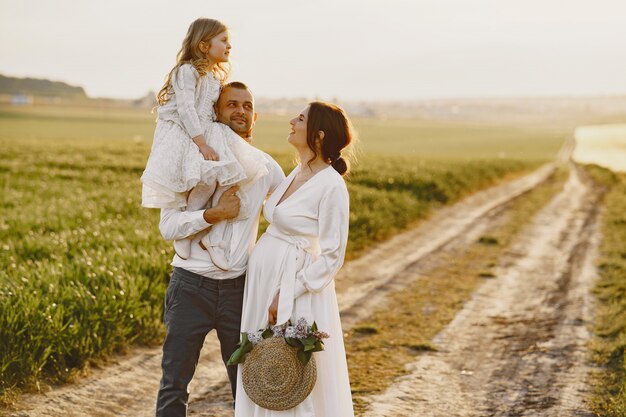 Family with little daughter spending time together in sunny field