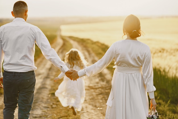 Free photo family with little daughter spending time together in sunny field