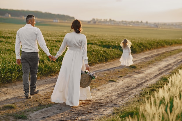 Family with little daughter spending time together in sunny field