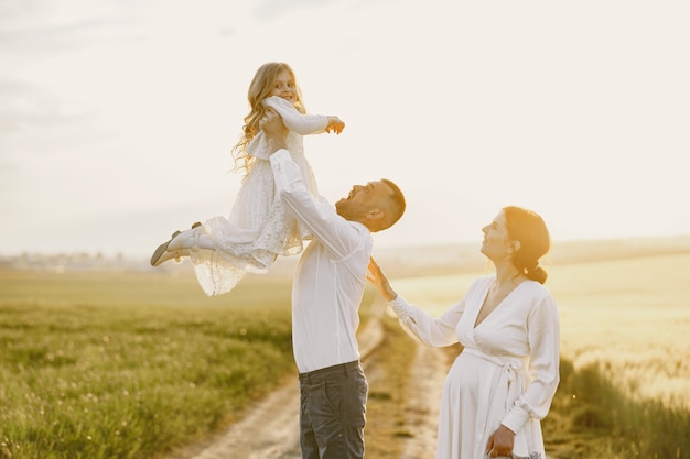 Family with little daughter spending time together in sunny field