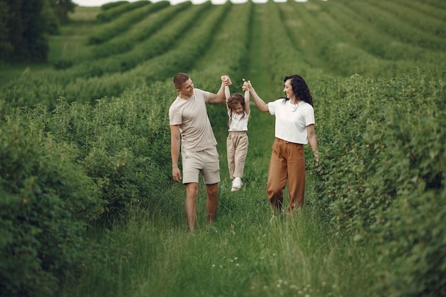 Family with little daughter spending time together in sunny field