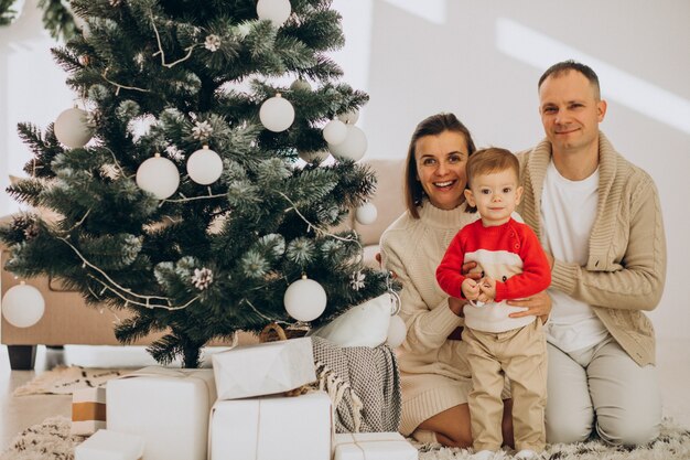 Family with little son on Christmas by christmas tree at home