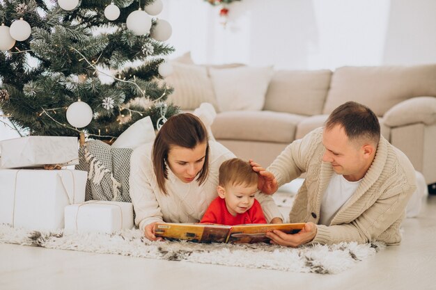 Family with little son on Christmas by christmas tree at home