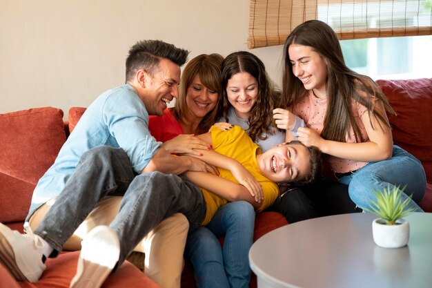 Семья с родителями и детьми вместе веселятся на диване