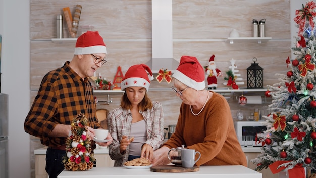 一緒にクリスマスを楽しんでクリスマス休暇をスピードアップするサンタ帽子を持つ家族