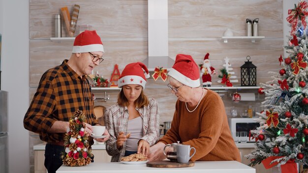 一緒にクリスマスを楽しんでクリスマス休暇をスピードアップするサンタ帽子を持つ家族
