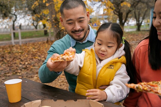 Family with tasty pizza outside side view