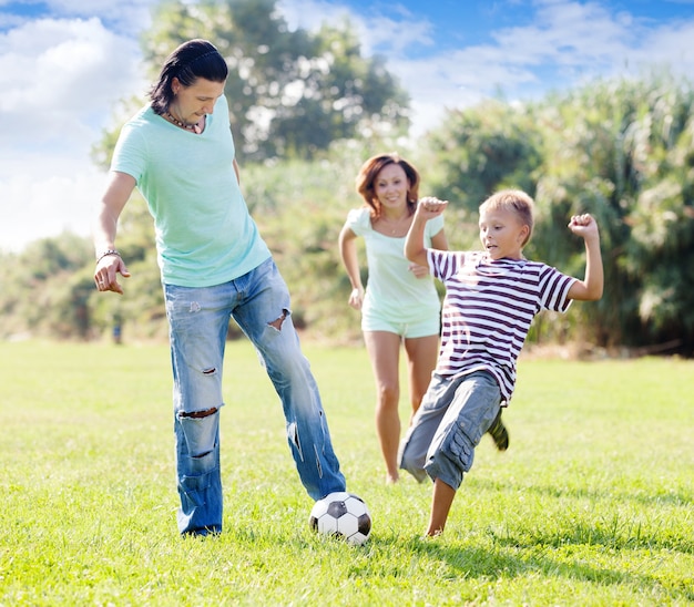 семья с ребенком подросток, играя с футбольным мячом