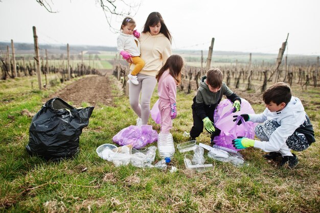 ブドウ園で掃除しながらゴミを集めるゴミ袋を持っている家族環境保全とエコロジーリサイクル