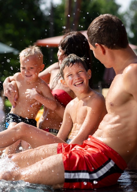 Foto gratuita famiglia con due bambini che si godono la giornata in piscina