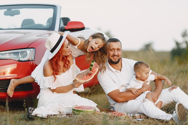 Family with watermelon. Father in a white t-shirt. People in a picnic.