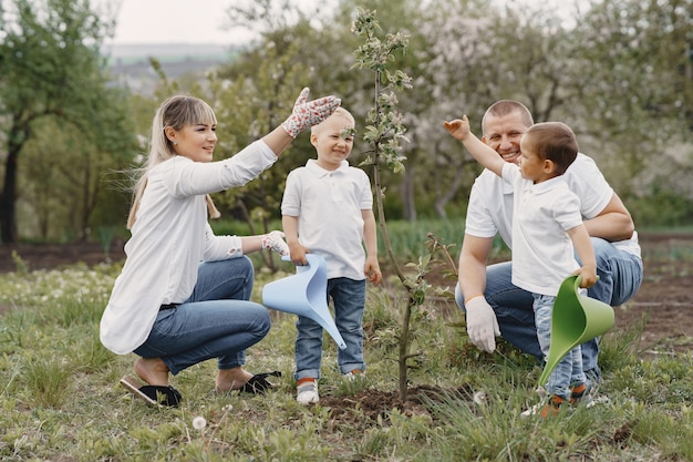 작은 아들이있는 가족은 마당에 나무를 심고 있습니다.