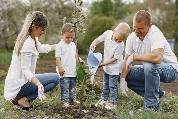 小さな息子と家族が庭に木を植えています