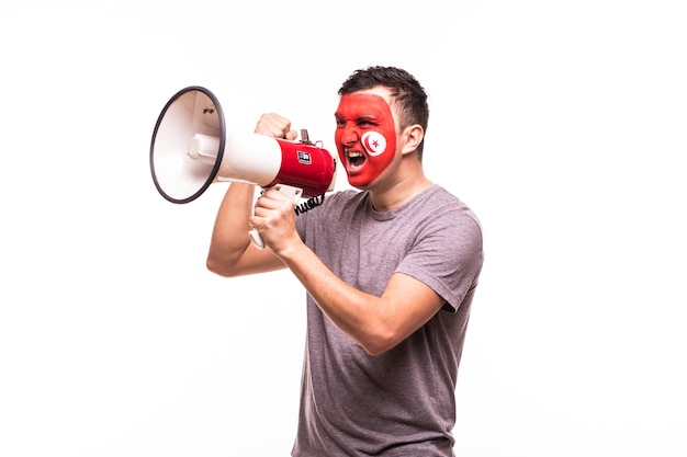 Fan support of Tunisia national team with painted face shout and scream on megaphone isolated on white background