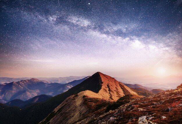 우크라이나의 산에서 환상적인 풍경입니다. 별과 성운과 은하계의 활기찬 밤하늘.