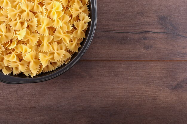 farfalle pasta in bowl top view with copy space on brown wooden surface