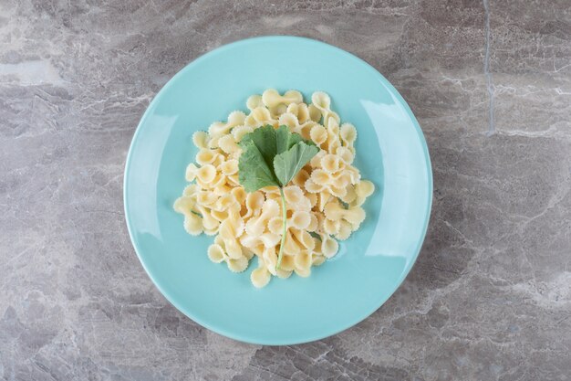 Farfalle pasta with greens on the plate , on the marble.