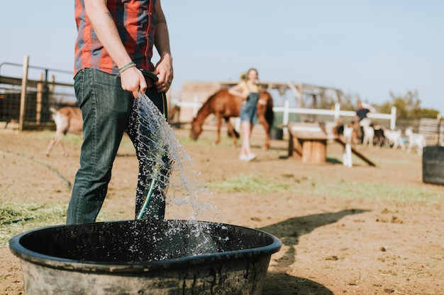 Free photo farmer filling a tub with water