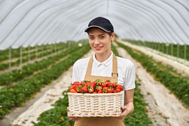 Farmer woman holding wicker basket with tasty strawberries