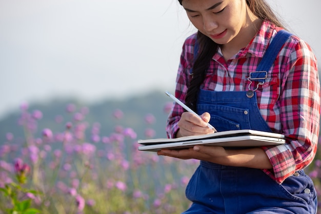 農家の女性は花畑でメモを取っています。