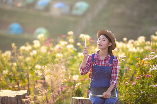 농부 여성은 꽃밭에서 메모를하고 있습니다.