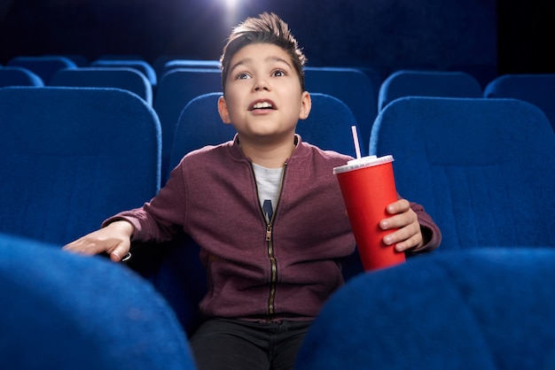 Fascinated teenager watching movie attentively in cinema.