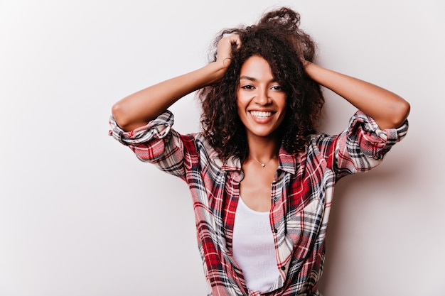 Fascinating african lady with happy face expression playing with her short hair. portrait of glad black girl isolated on white.