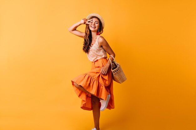 ポジティブな感情を表現する魅力的な赤毛の女性笑顔で踊るオレンジ色のスカートで幸せな生姜の女の子