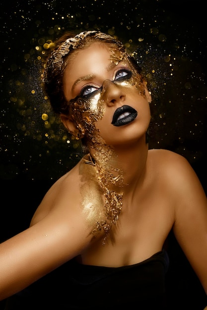 Fashion art golden skin girl model with festive golden glamor brilliant professional makeup