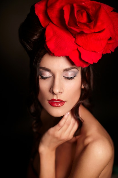 머리에 큰 빨간 장미와 함께 밝은 메이크업과 붉은 입술을 가진 아름 다운 여자 패션