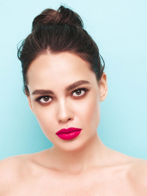 Free photo fashion beauty portrait of young brunette woman with evening stylish makeup and perfect clean skin sexy model with hair in a bun posing in studio with pink bright natural lips