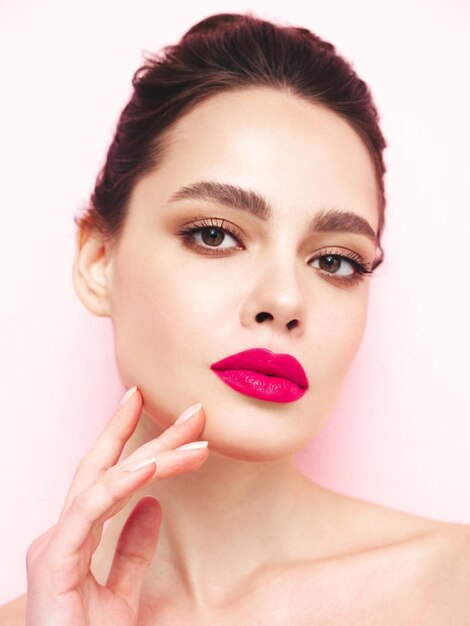 Fashion beauty portrait of young brunette woman with evening stylish makeup and perfect clean skin Sexy model with hair in a bun posing in studio With pink bright natural lips