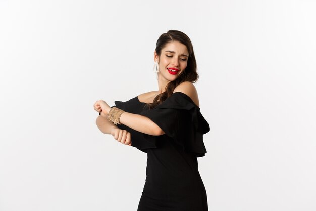 Fashion and beauty.  woman feeling happy and dancing in black party dress, standing carefree against white background.