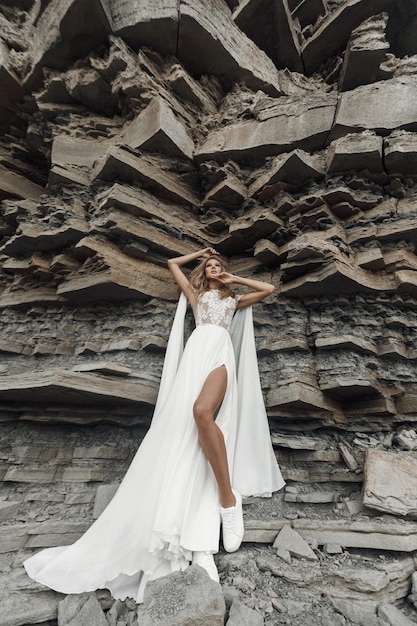 Free photo fashion bride in wedding dress near rocks