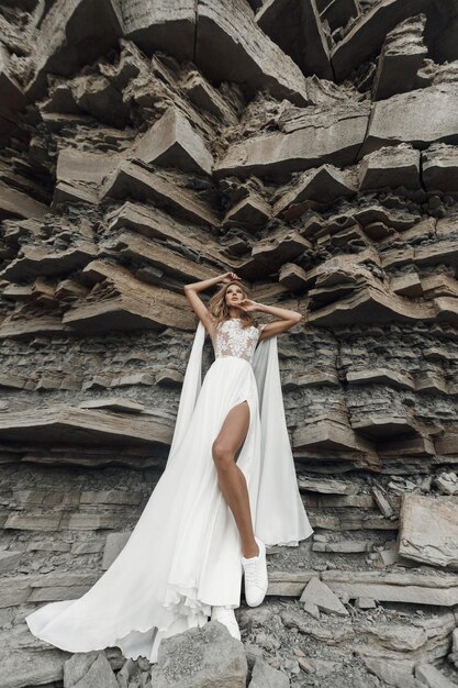 岩の近くのウェディングドレスのファッション花嫁