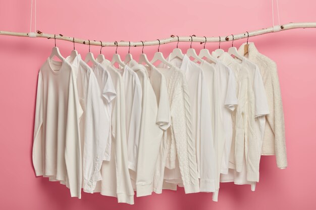 Модная одежда белого цвета, вязаные узоры, вешается на вешалки для демонстрации. Ряд солидных нарядов в гардеробе.