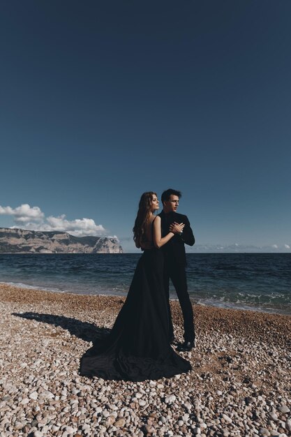 модная пара в черном платье и костюме на открытом воздухе