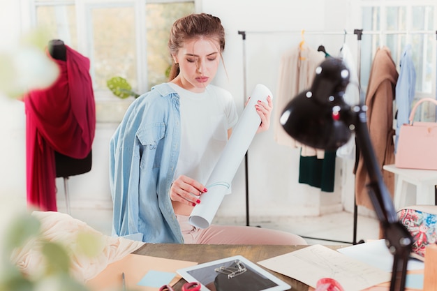 Fashion designer woman working in studio sitting on the desk