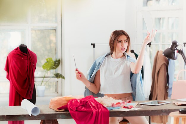 Fashion designer working in studio sitting on the desk