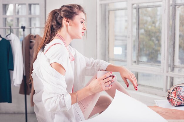 Fashion designer working in studio sitting on the desk