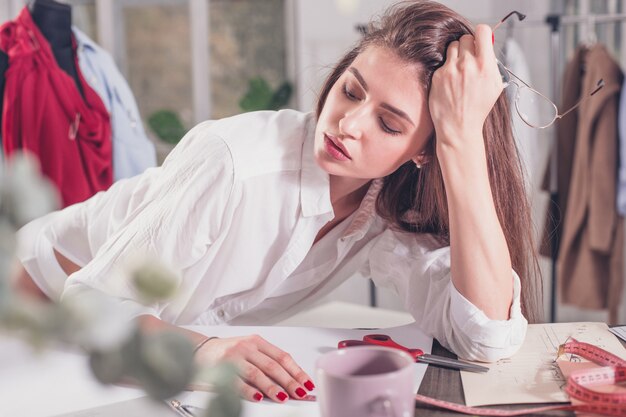 Fashion designer working in studio sitting on the desk