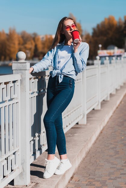 Мода одетая женщина держит чашку кофе