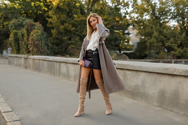 Fashion full length image of elegant  blond  woman in stylish luxury beige leather  coat and hight heels, walking  outdoor
