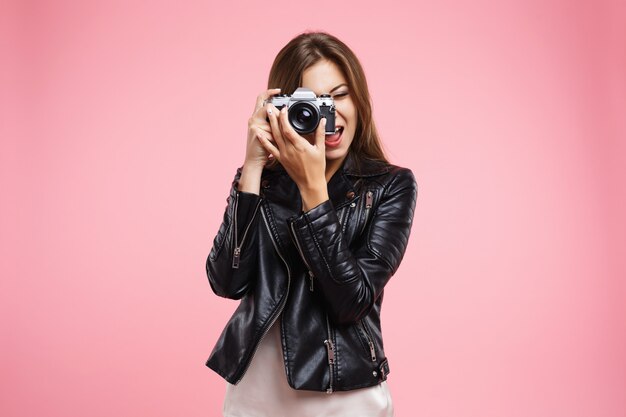 Fashion girl in black leather jacket holding old camera