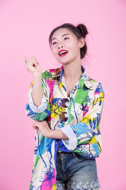 Fashion girl dress up with hand gestures on a pink background.