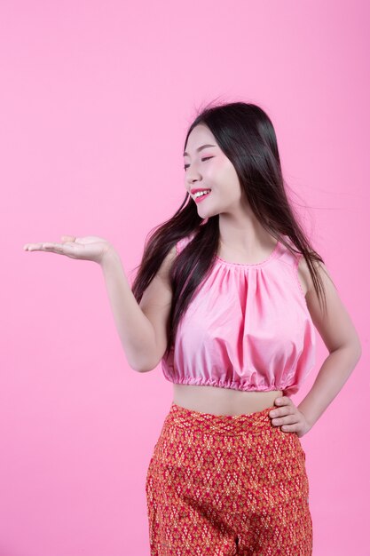 Fashion girl dress up with hand gestures on a pink background.