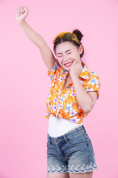 Free photo fashion girl dress up with hand gestures on a pink background.