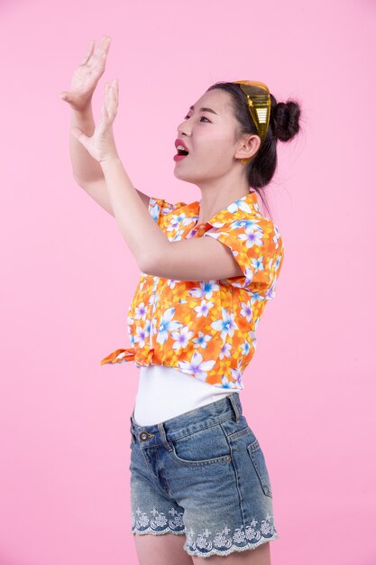 Fashion girl dress up with hand gestures on a pink background.